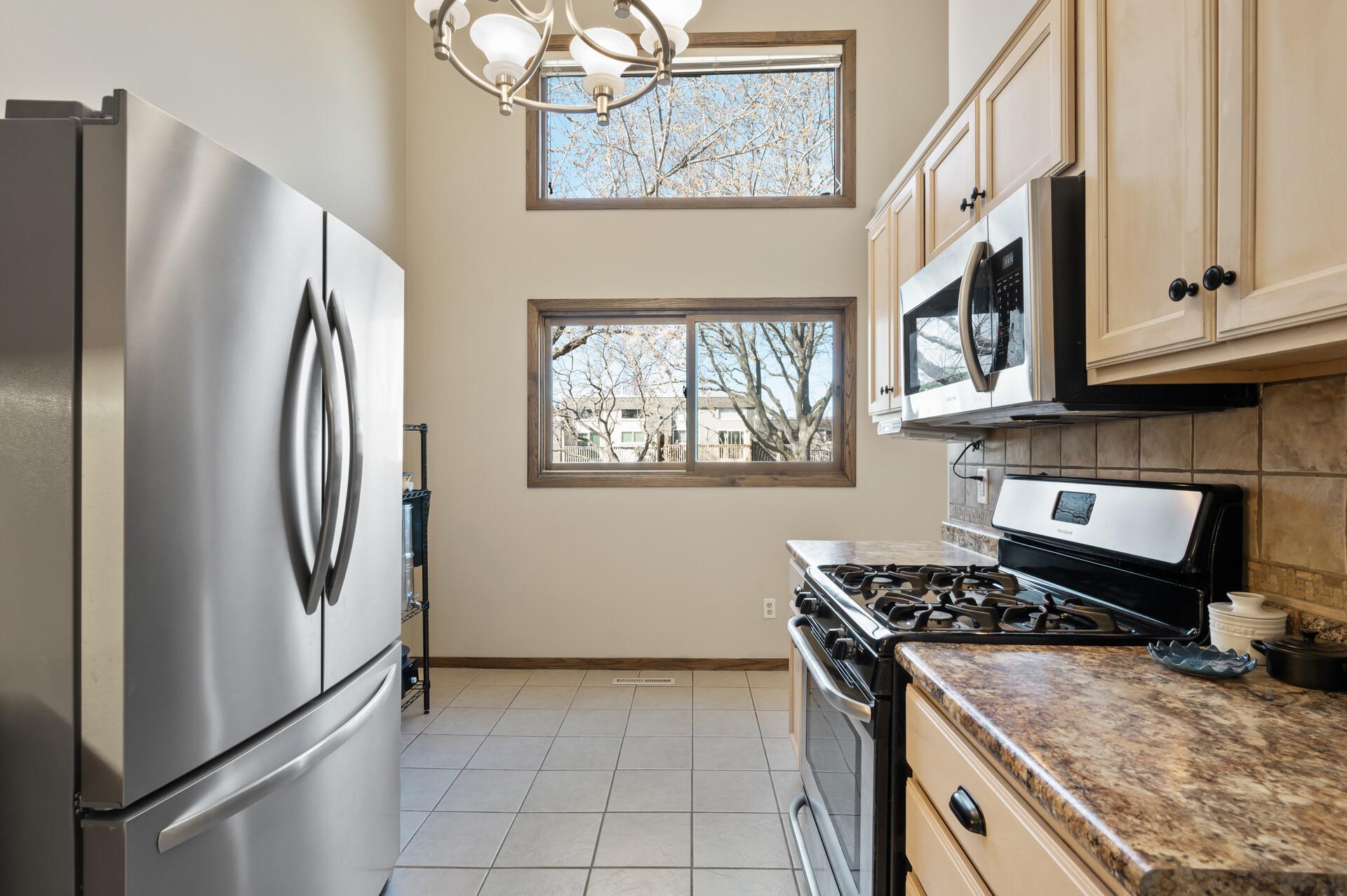 The kitchen is bright and airy with stacked windows that look out to the green space in the backyard.