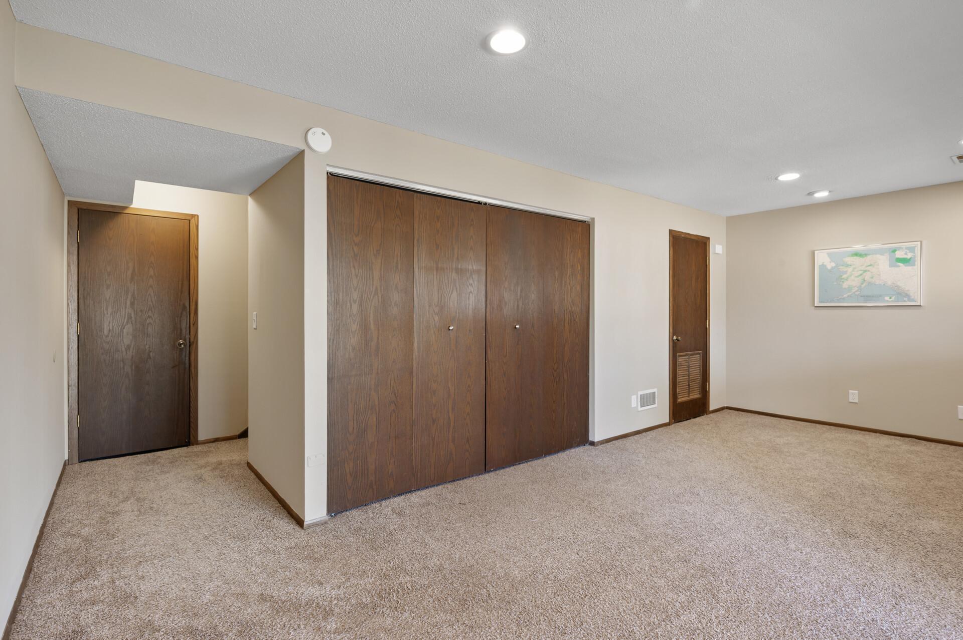 In this reverse view of the lower level you will find the utility room on the far end, the laundry closet, and the door at the bottom of the stairs is a large crawl space with shelves for storage.