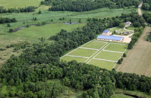 Aerial looking back at pastures and buildings
