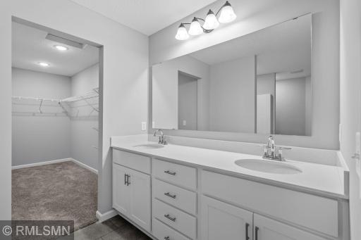 (Photo of previously finished home) The luxurious owner's suite features a spacious, elegant bathroom with dual vanities, leading into an oversized walk-in closet that offers ample storage space.