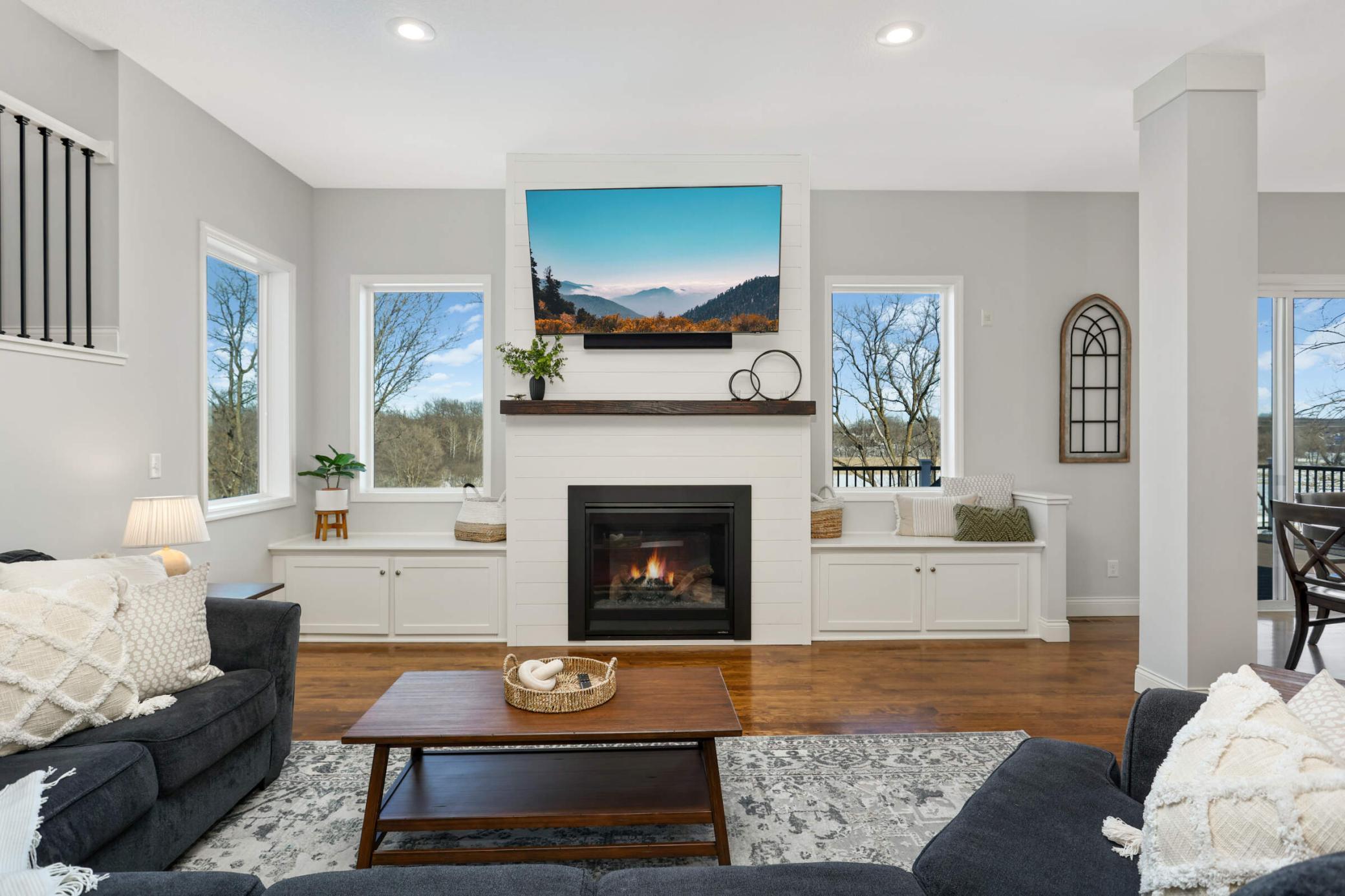Fireplace with shiplap surround flanked by windows and built-in cabinetry.