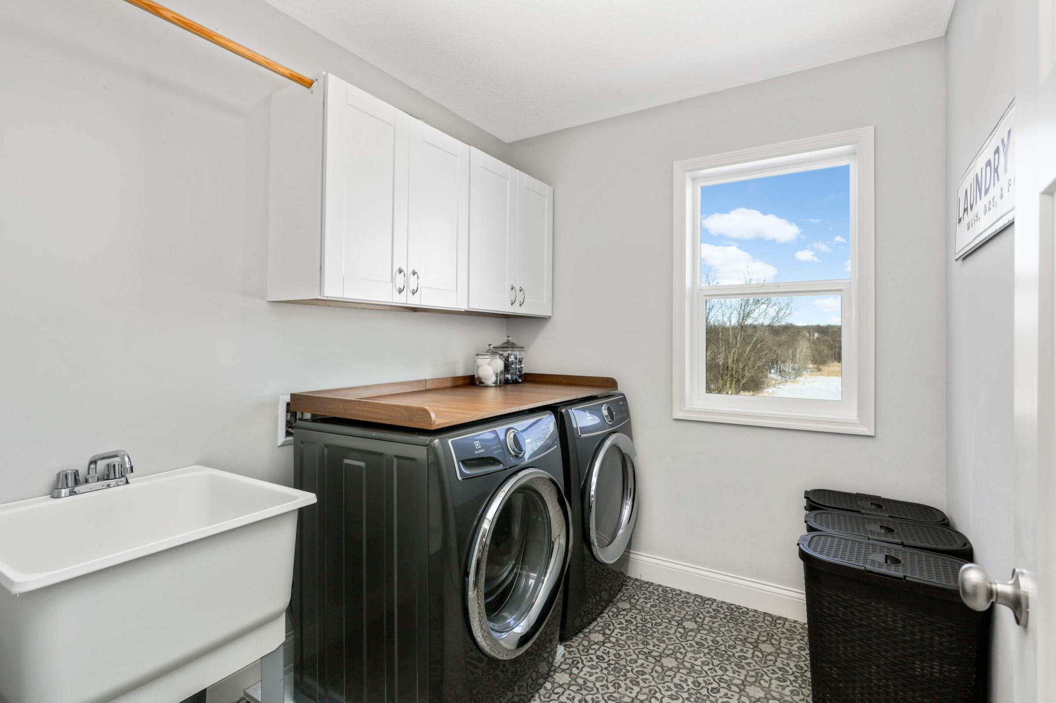 Upper level laundry room with utility sink and cabinets!