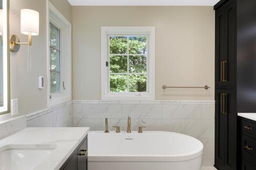 A luxurious private bathroom features heated floors, a massive walk-in shower, a separate soaking tub, separate double vanities with fog resistant LED mirrors, and a private commode room.