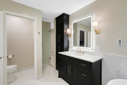 A luxurious private bathroom features heated floors, a massive walk-in shower, a separate soaking tub, separate double vanities with fog resistant LED mirrors, and a private commode room.