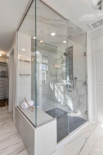 The spacious walk-in shower features custom luxurious glass detail.