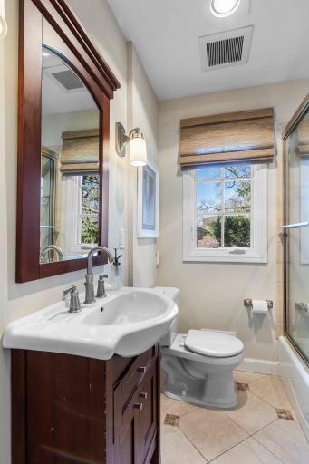 These bedrooms share a hallway leading to a full bathroom equipped with a tub-shower combination with tile surround, heated tile flooring and a linen closet for added convenience.