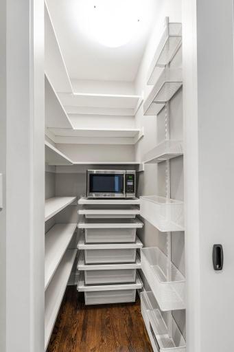 A spacious walk-in pantry with custom organization and a riverbed granite center island with added storage ensuring both beauty and efficiency.