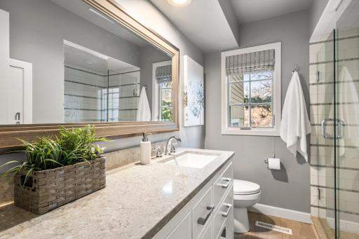 This stylish 3/4 bathroom, conveniently located off the laundry room, features a beautifully tiled shower and a stunning vanity that adds a touch of elegance.