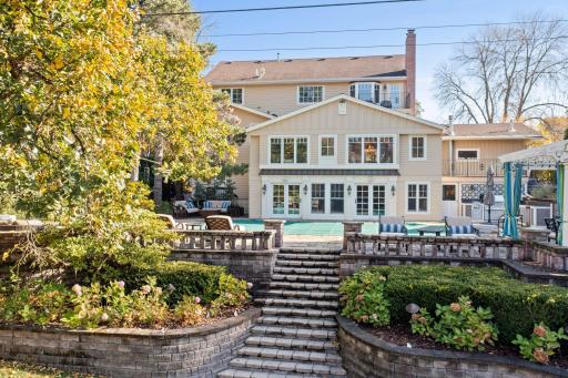This large back patio offers ample space for outdoor entertaining and relaxation, featuring grand stairs that lead down to the expansive backyard.