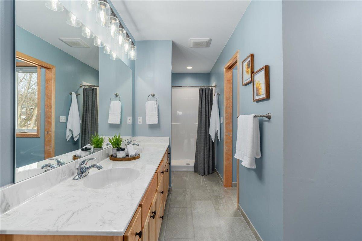 Primary private bathroom with 2 sinks and tile floors
