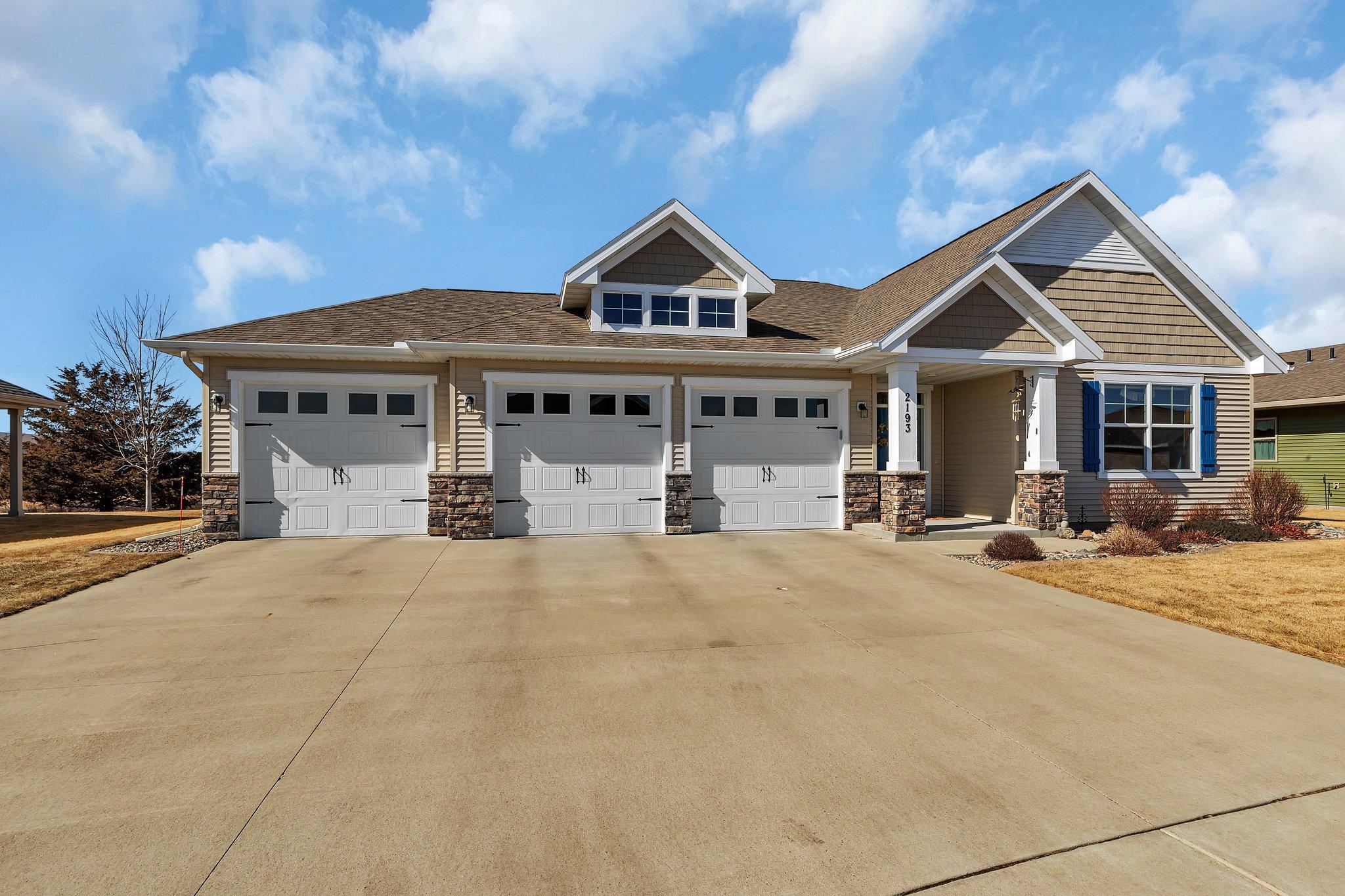 Three stall garage with a driveway accommodating multiple vehicles.