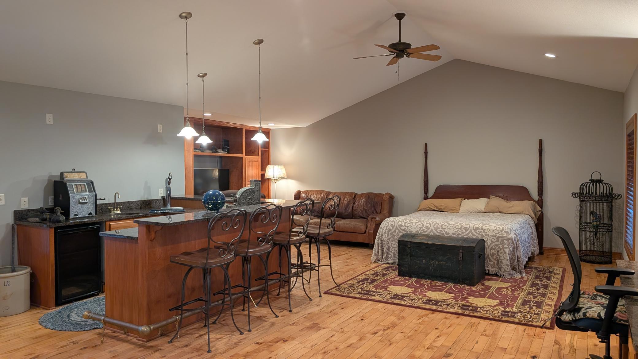 This large upper-level bedroom is a unique and functional space, complete with a wet bar, kegerator, and built-in entertainment center.