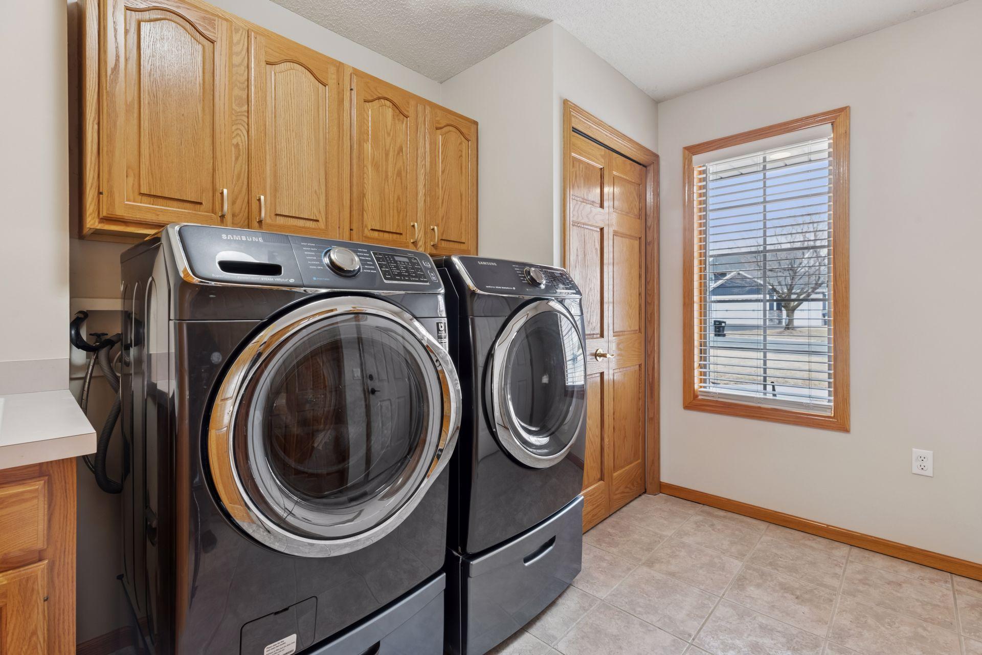 Located just off the garage entrance, this space is equipped with a high-efficiency Samsung HE washer and dryer combo, both set on pedestals for easy access and added storage.