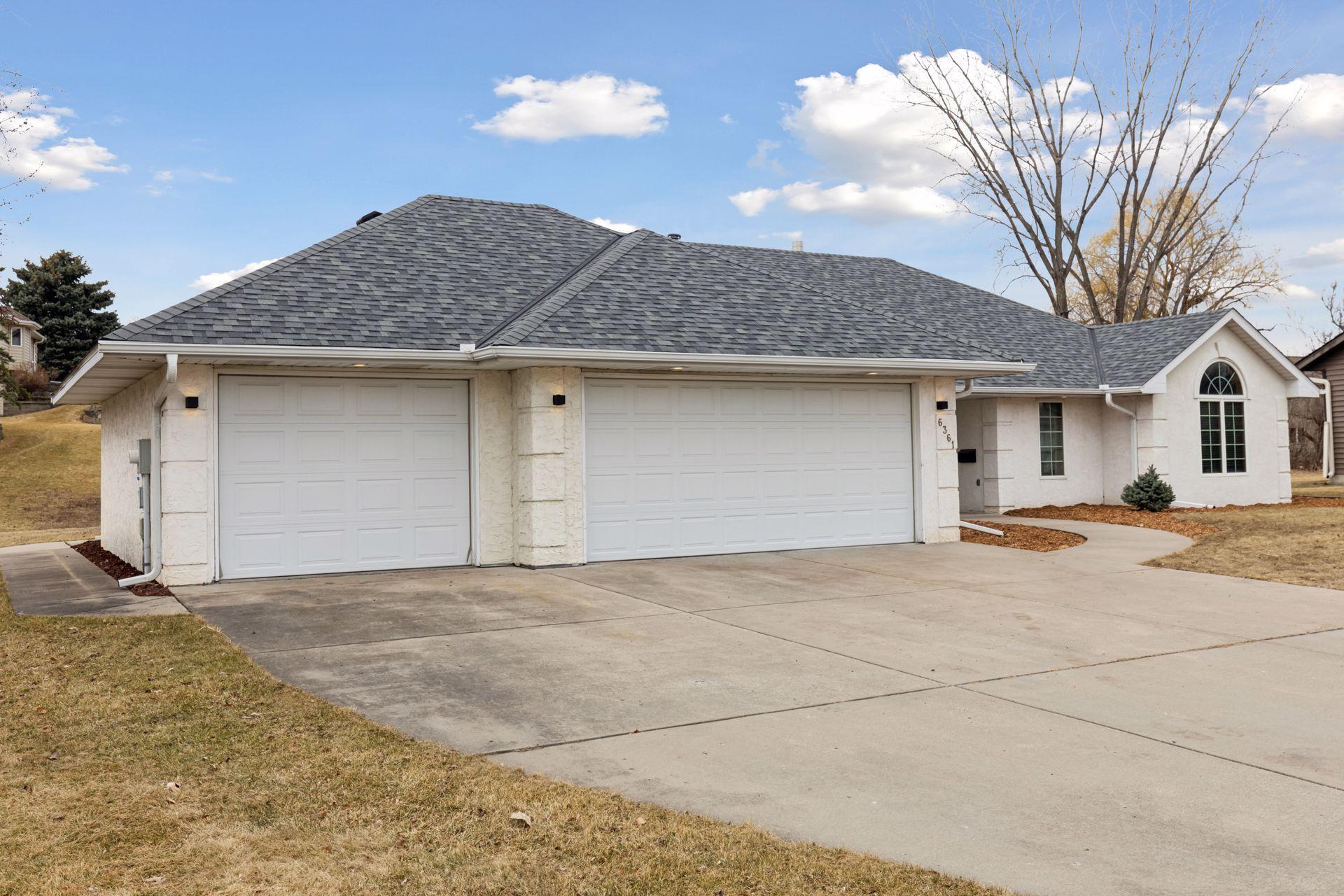 The spacious concrete three-car driveway offers ample parking and adds to the home's impressive facade.