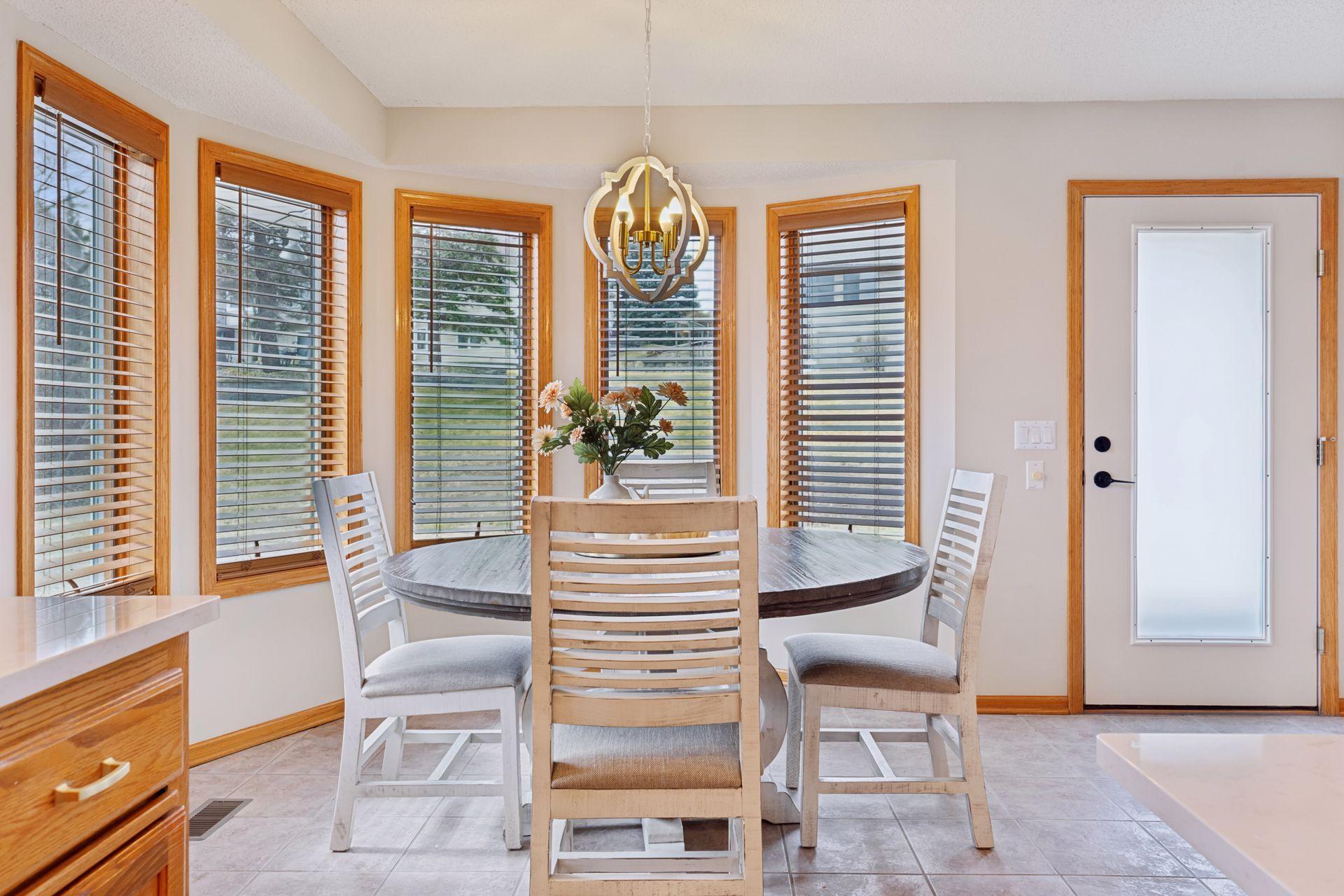 Adjacent to the kitchen, the dining area is a sun-drenched retreat, surrounded by windows that bring the outdoors in and a door that leads directly to the back patio—ideal for alfresco dining or simply enjoying the fresh air.