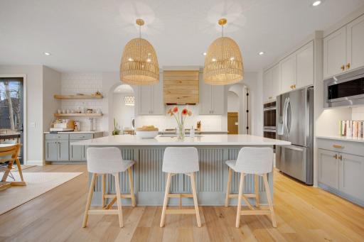 Gorgeous Kitchen with oversized island, enameled cabinetry, custom lighting, gourmet hood, tile backsplash, generous counter space and the beloved coffee/bar station.