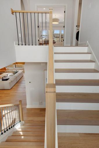 Custom stairwell flooring with white raisers, black balusters, and wood railing.