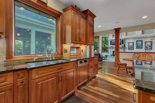 The eat-in kitchen is bathed in natural light and seamlessly connects to the outdoors through a sliding door, leading to a lakeside deck and a screened gazebo—ideal for enjoying meals or relaxing with beautiful lakefront scenery.
