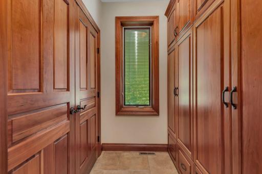 This well-organized storage area, conveniently located by the garage and laundry room, offers ample space for stowing away indoor and outdoor essentials. Custom-built cabinetry provides generous storage, keeping the space neat and functional.
