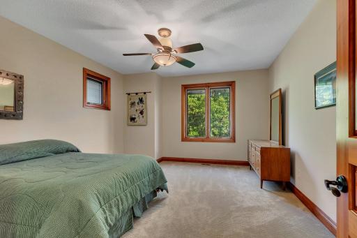This spacious bedroom is the third of six bedrooms located on the upper level , featuring a large window that offers scenic views. It includes a generous walk-in closet, providing ample storage space for clothing and personal items.