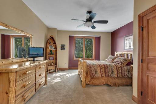 The fifth of six bedrooms, located on the upper level, offers a peaceful retreat with beautiful lake views. This room exudes warmth and coziness perfect for guests or family members seeking comfort with a scenic backdrop.