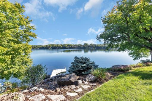Stone steps lead down to the shore, surrounded by natural foliage, enhancing the peaceful and private atmosphere of the lakeside retreat.