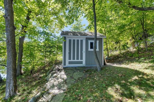 Tucked among the trees, this charming lakeside shed is the perfect hideaway for all your lake toys and gear—just steps from the water, ready for fun-filled adventures!