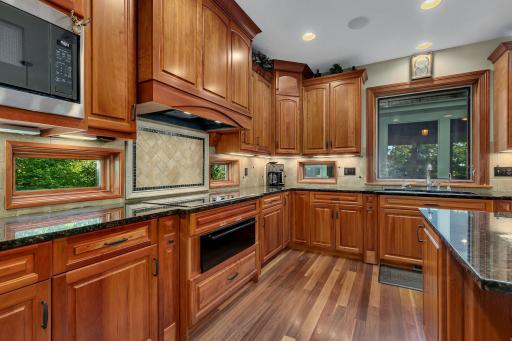 This kitchen features a sleek, integrated cooktop with warming drawer below. The beautiful tile backsplash, with a detailed herringbone pattern and framed border, serves as a stunning focal point behind the cooktop.