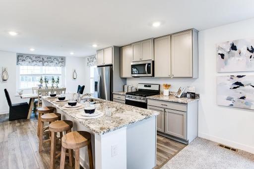 Highlighting this stunning kitchen is this 9-foot granite island! Easy seating for 4. Also has a gas range, and microwave hood vented to exterior. Photo of end unit model, colors are similar.