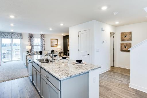 View from the dining area looking through the kitchen and into the living room. Large pantry and half bath located on this floor as well. Photo of end unit model, colors are similar.
