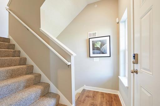 Entry from front door of home. Head upstairs to the main level kitchen-dining-living or head down to the garage and flex room. Photo of end unit model, colors are similar.