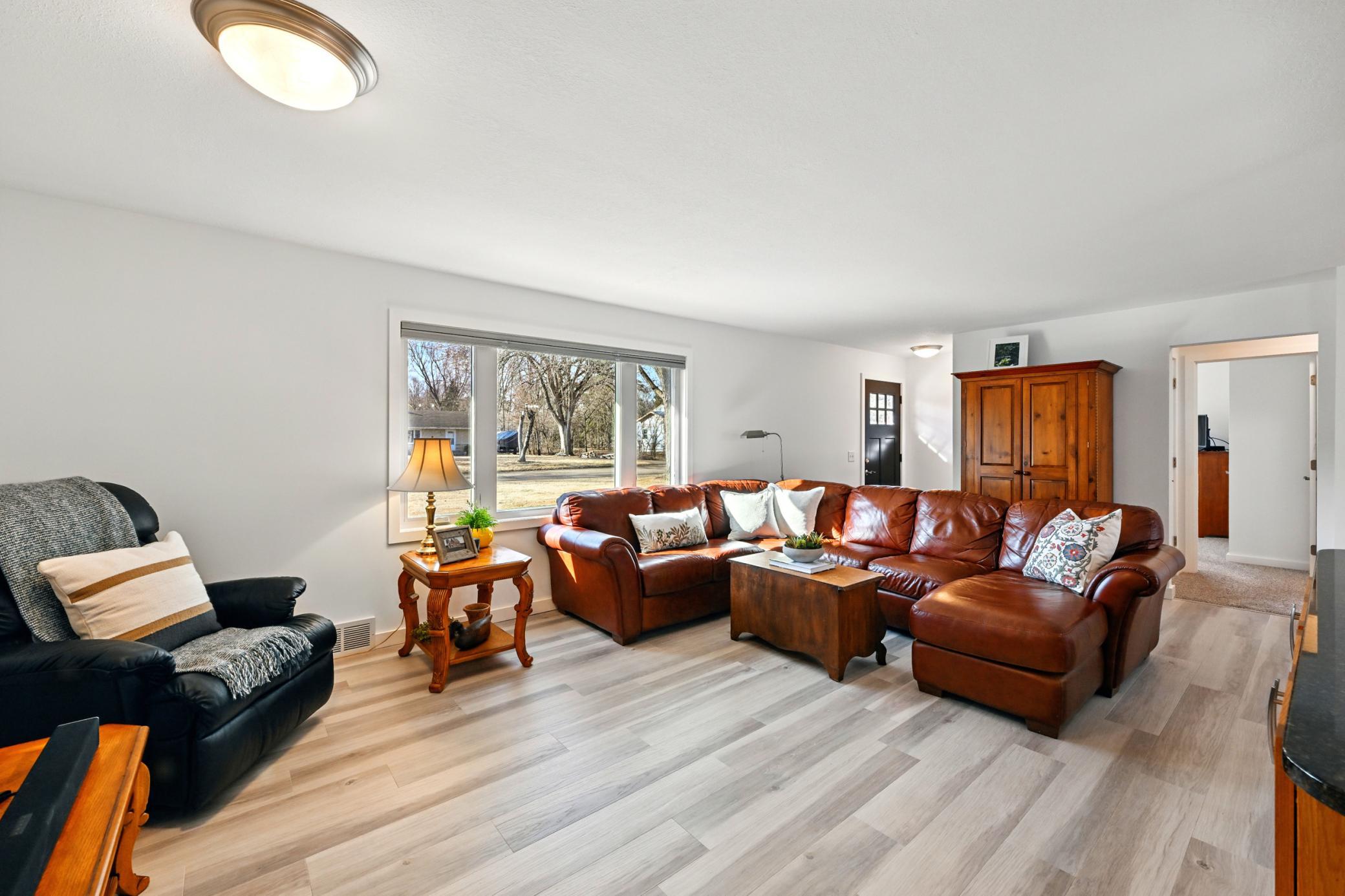 Main level living room with new flooring throughout and views of the front yard