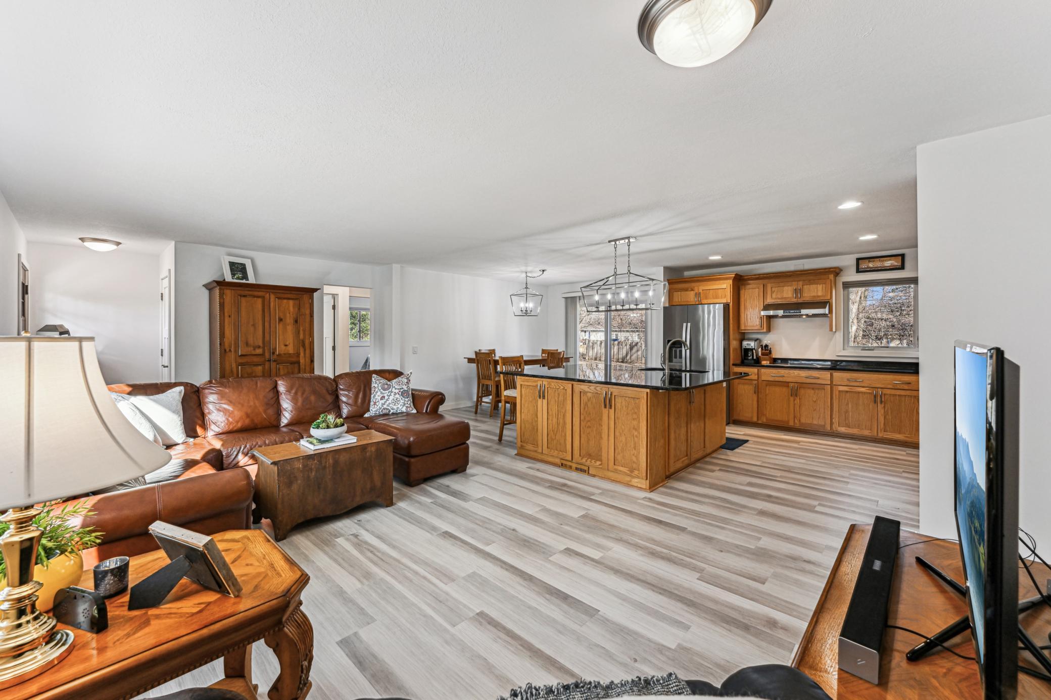 Open concept main level living room, dining room and kitchen with new flooring and recessed lights