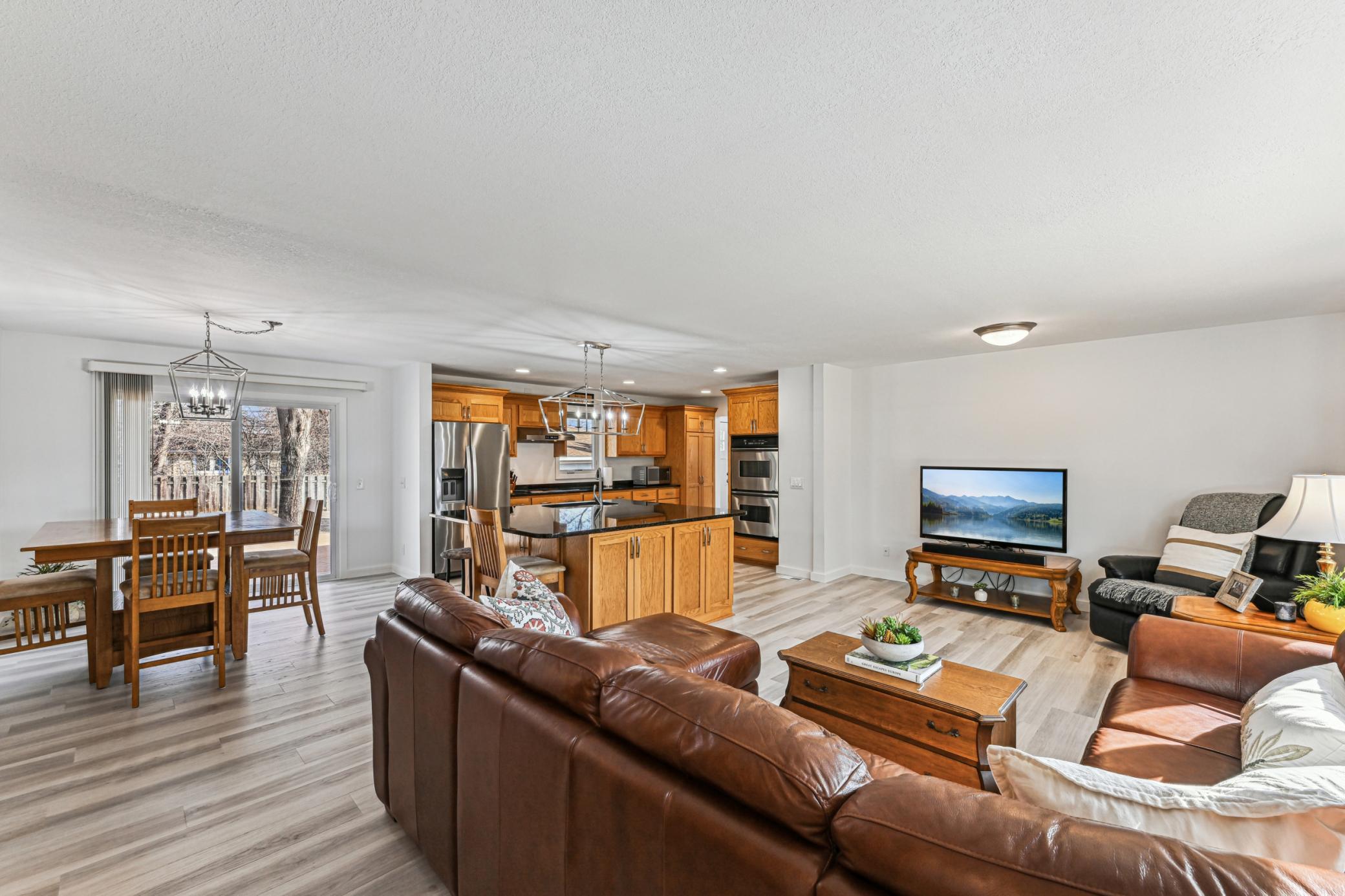 Open concept main level living room, dining room and kitchen with new flooring.