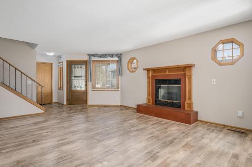 Spacious and bright living room featuring a fireplace with custom wood and tile surround, ideal for relaxing.