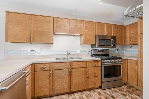 Updated kitchen features stainless steel appliances, gas range, ample cabinetry, and modern tile backsplash.
