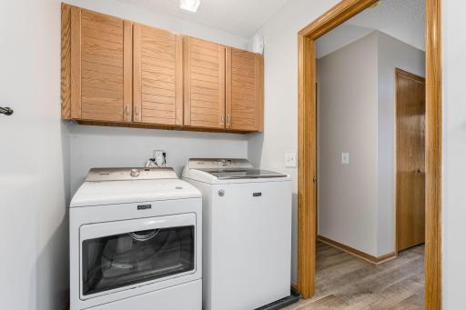 Spacious laundry nook with upper cabinetry and washer/dryer.