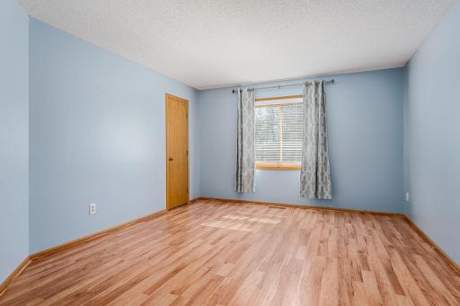 Spacious and serene primary bedroom with large window and soft blue tones.
