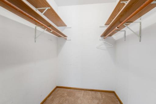 Walk-in closet with shelving and ample hanging space.