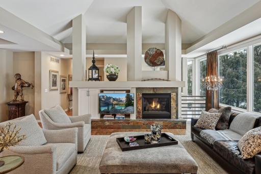 Living room with vaulted ceilings, gas fireplace, wall of windows and open to kitchen.