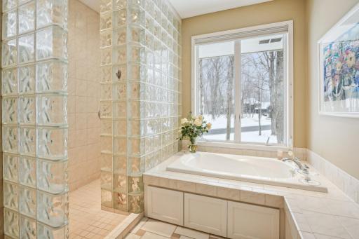 Primary bathroom with double vanity, separate tub and shower, and walk in closet.