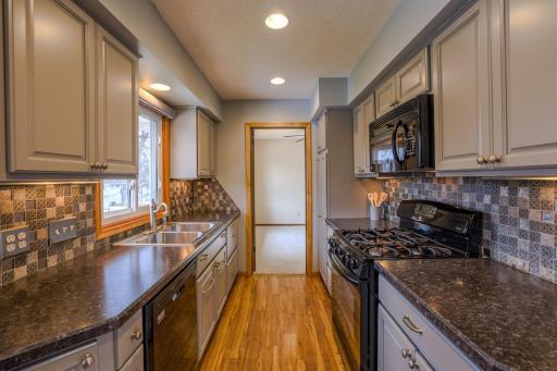 Functional Galley Kitchen Layout- Efficient galley-style layout with cabinetry on both sides for optimal workflow. Recessed lighting, updated backsplash tile, refreshed cabinets, and coordinating countertops reflect the 2016 remodel.