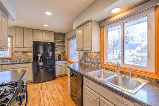 Kitchen - Remodeled in 2016, this kitchen features painted cabinetry, dark countertops, and a mosaic tile backsplash. A double-basin stainless sink sits beneath a large window, bringing natural light into the workspace.