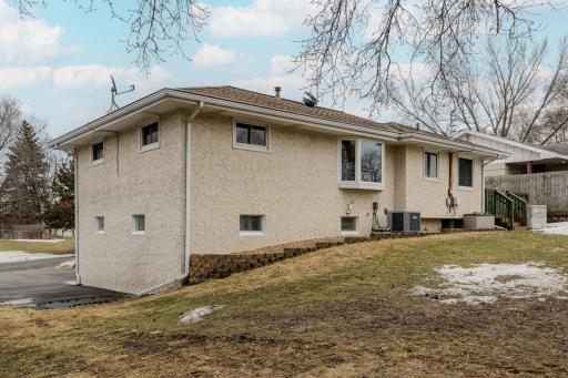 Rear/Side Exterior â Angled rear and side view highlights the stucco exterior, updated windows, and additional parking beside the home. Space accommodates a boat, trailer, or extra vehicle, adding flexibility and function to the 9,148 sq ft lot.