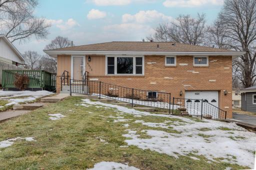 Front Exterior â Full front elevation features classic 1957 design with brick veneer, updated driveway (2021), and attached tuck-under garage. Elevated lot provides neighborhood views, while the composite deck adds outdoor living space.