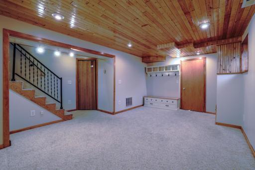 Lower level family room with door to garage at right and door to utility room by stairs to main level.