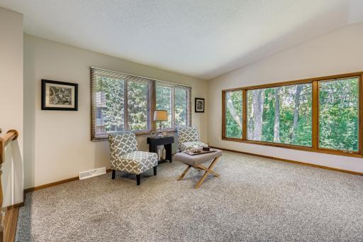 The living room features a host of windows that provide natural light and a pleasant view of the woods beyond