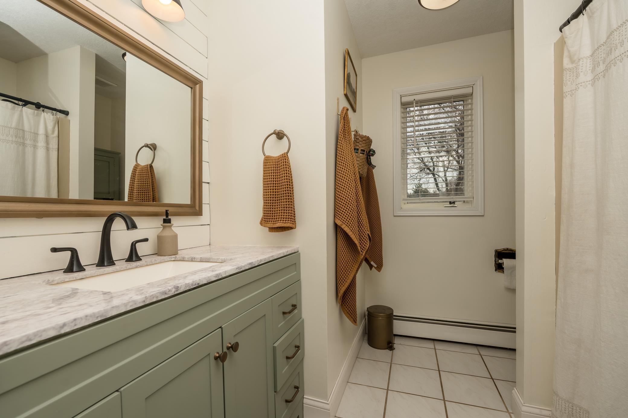 Main floor full bathroom that offers a new vanity, flooring, lighting, accent wall and more!