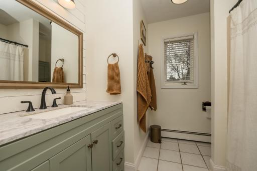 Main floor full bathroom that offers a new vanity, flooring, lighting, accent wall and more!