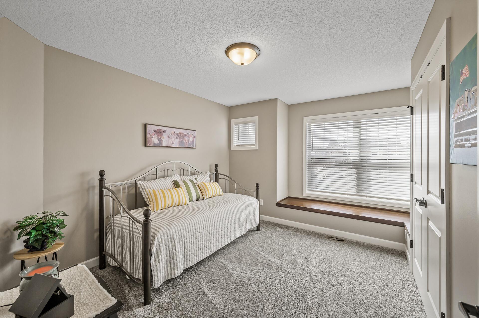 Second upper level bedroom features plush carpet, neutral paint and abundant natural light.